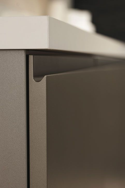 Gros plan de référence Arco : prise en main intégrée en profil J, usinée dans la façade sous le plan de travail.